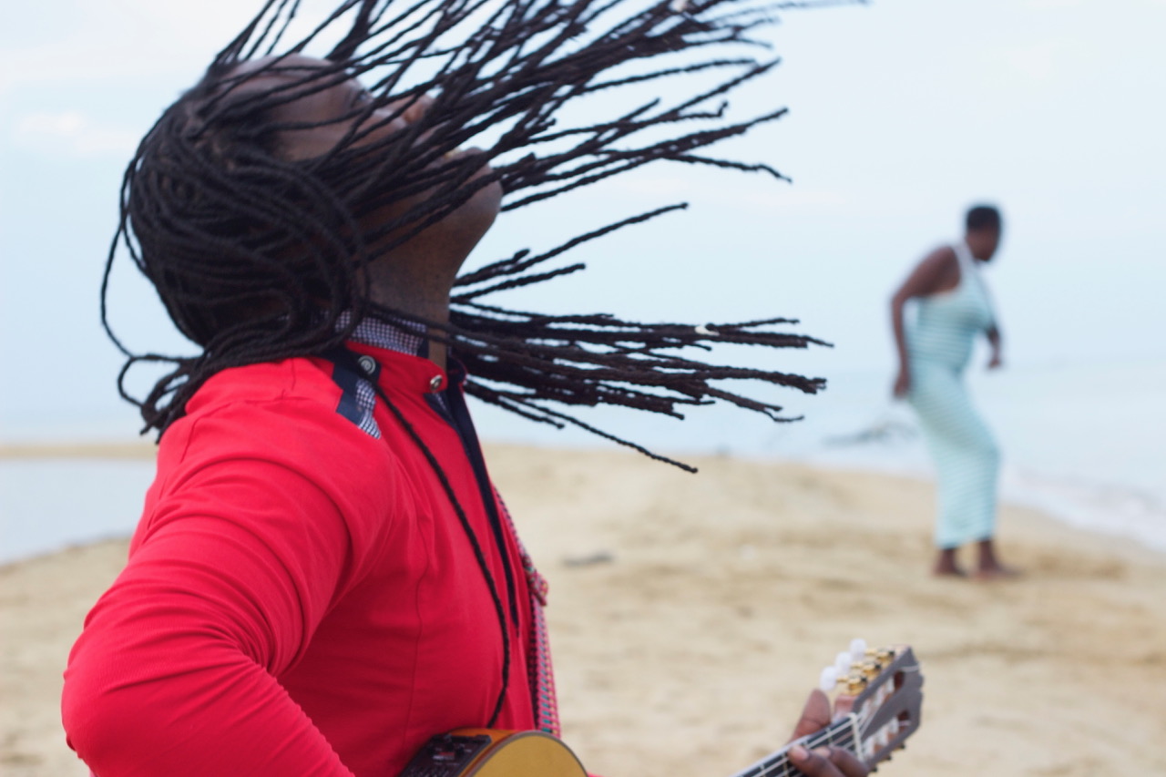 man in red shirt with guitar braids flying