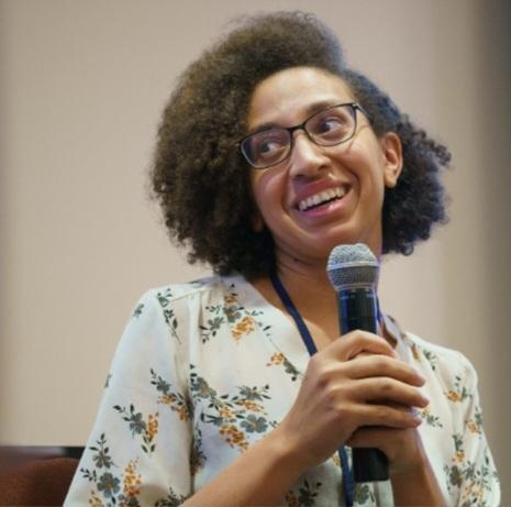 smiling woman in a floral top holding a microphone